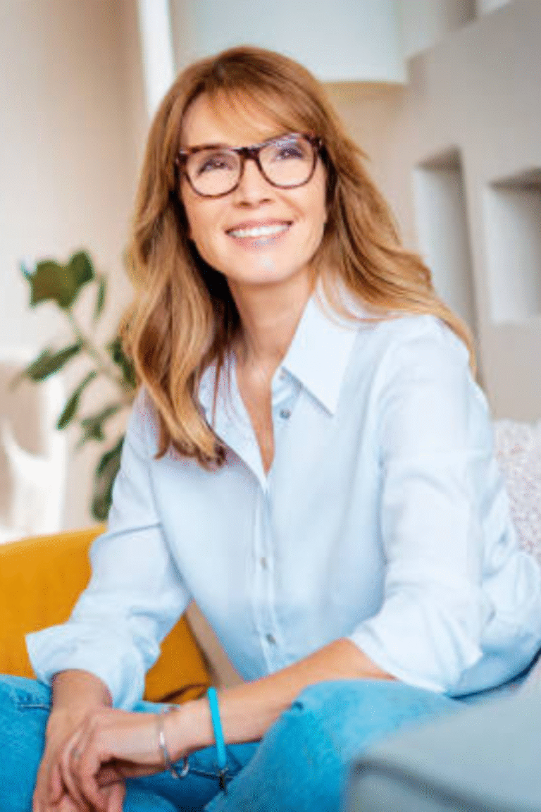 Smiling woman sitting comfortably on a couch, symbolizing balance, energy, and joy for the Dare On community